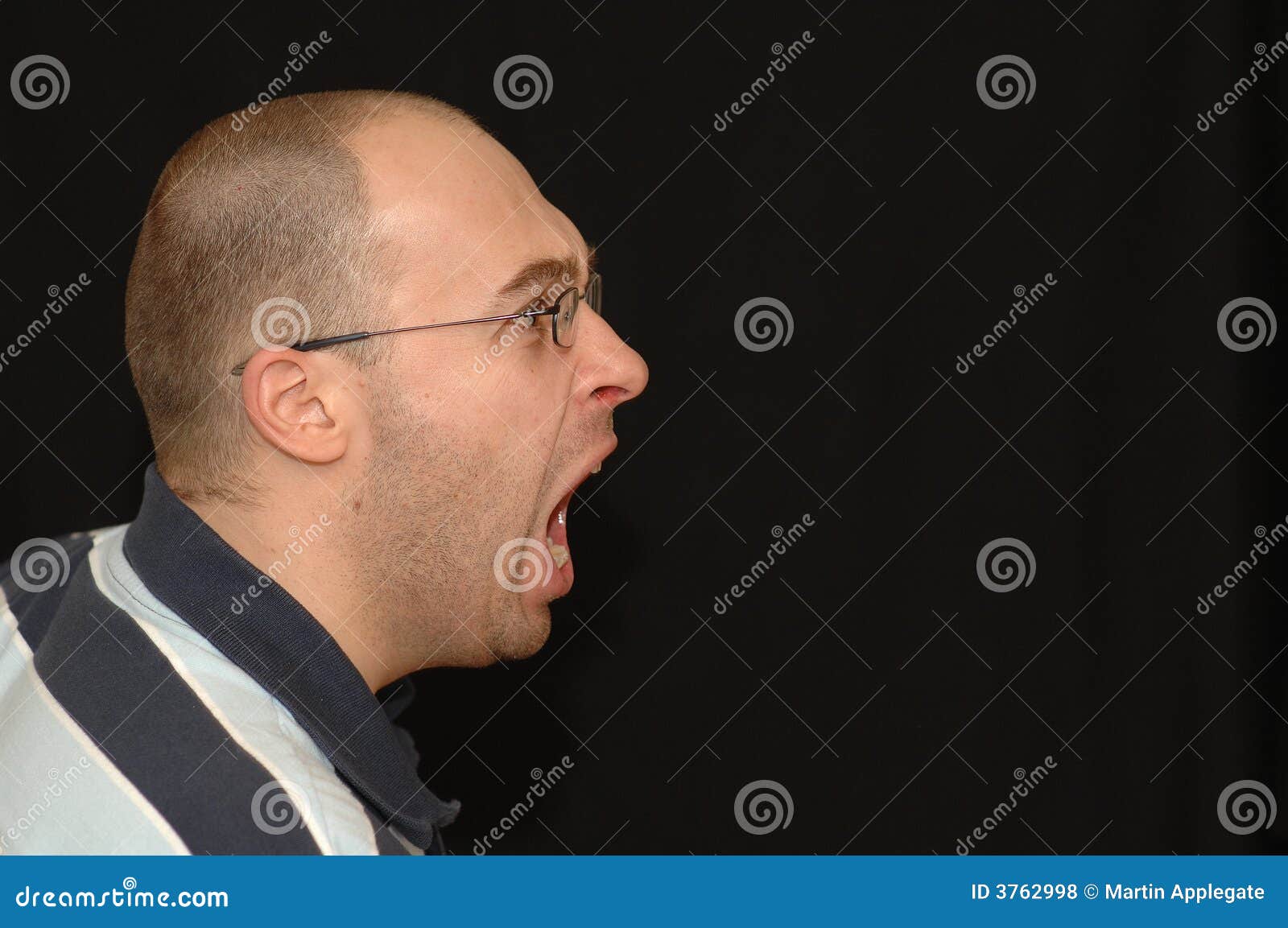 Shouting do homem. Vidros desgastando de um retrato caucasiano adulto novo do perfil da cabeça do homem branco que têm uma expressão irritada em sua face com a boca aberta que shouting e que grita na frente do fundo preto