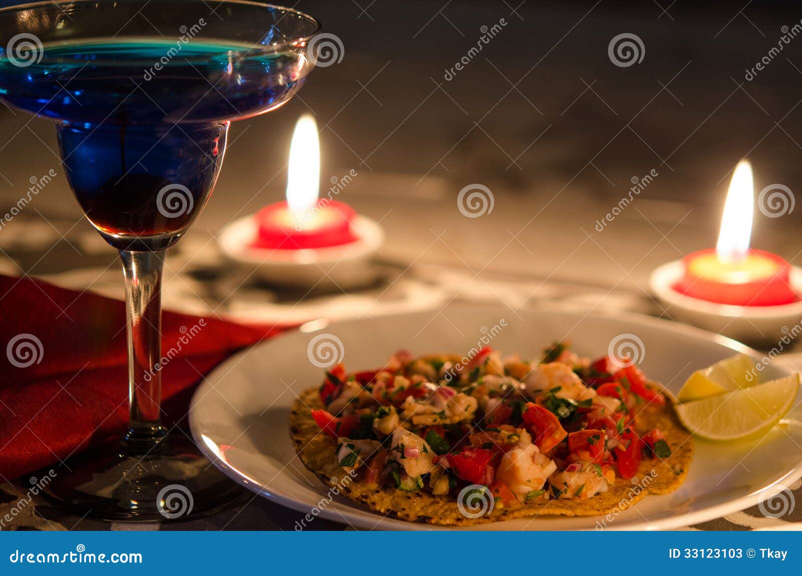 shrimp tostada with lime and blue cocktail and candles