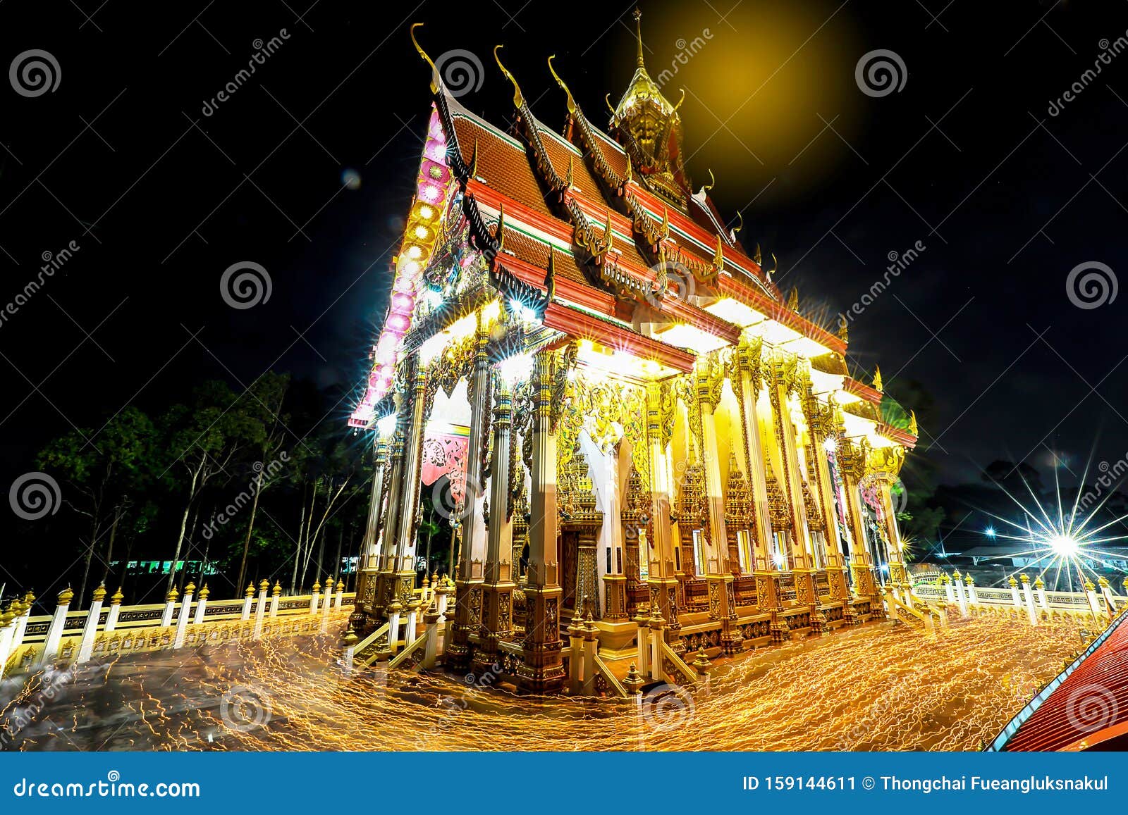 shutter bulbs image of triple circumambulation at the buddha church in night, people walking with candle light around buddha