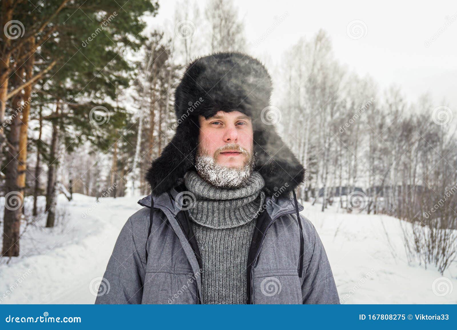 siberian russian man with a beard in hoarfrost in freezing cold in the winter freezes and wears a hat with a earflap
