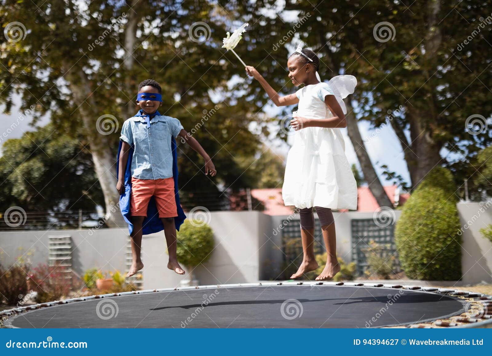 Siblings in Costumes Jumping on Trampoline Stock Image Image of male