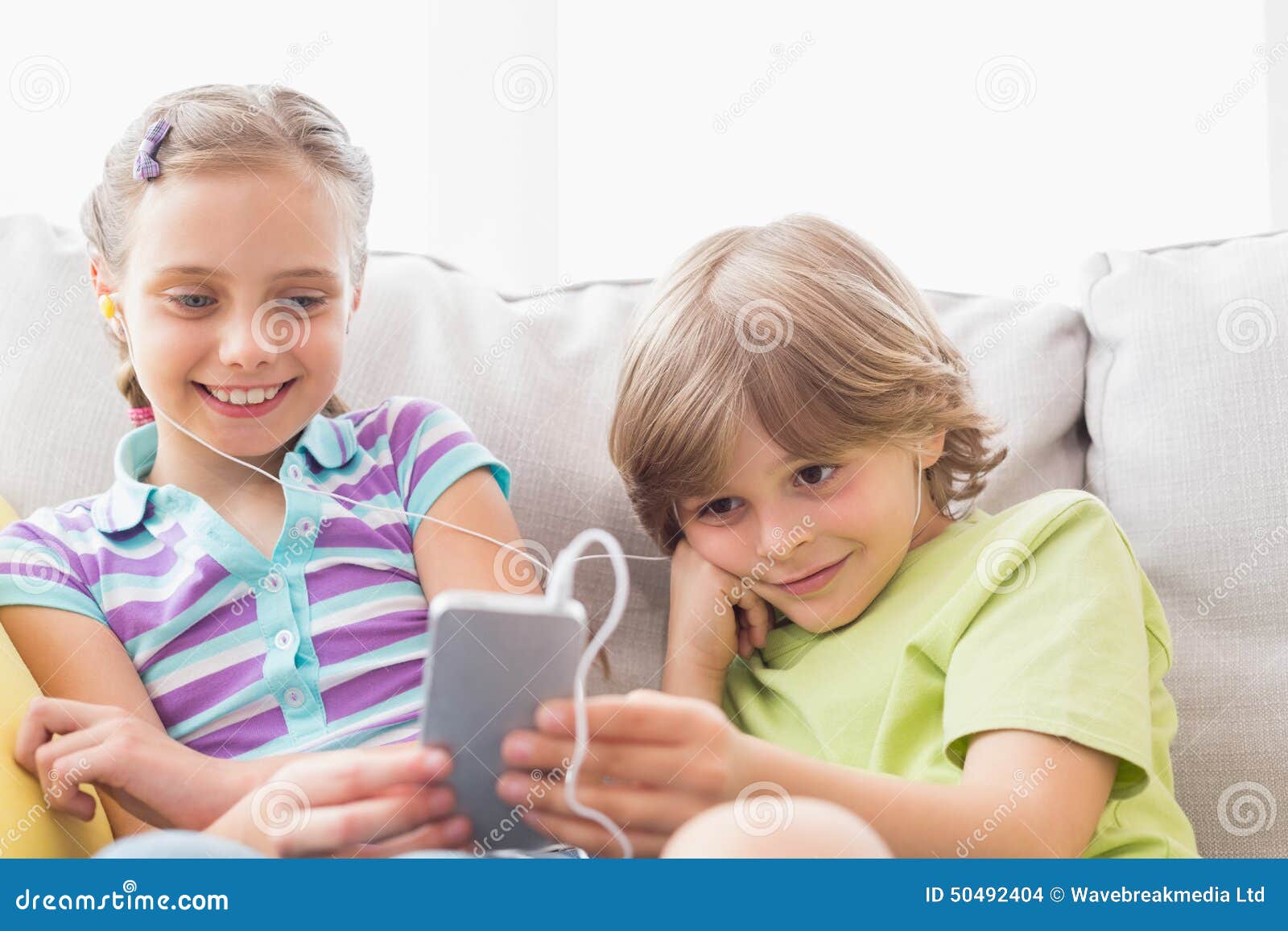 Siblings Listening Music through Mobile Phone at Home Stock Photo ...