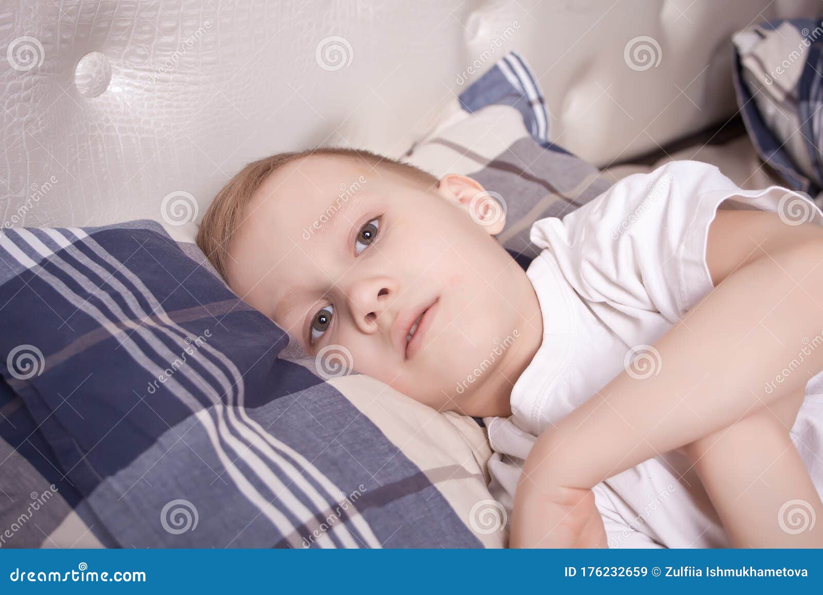 sick boy lies in bed and doesn t feel well