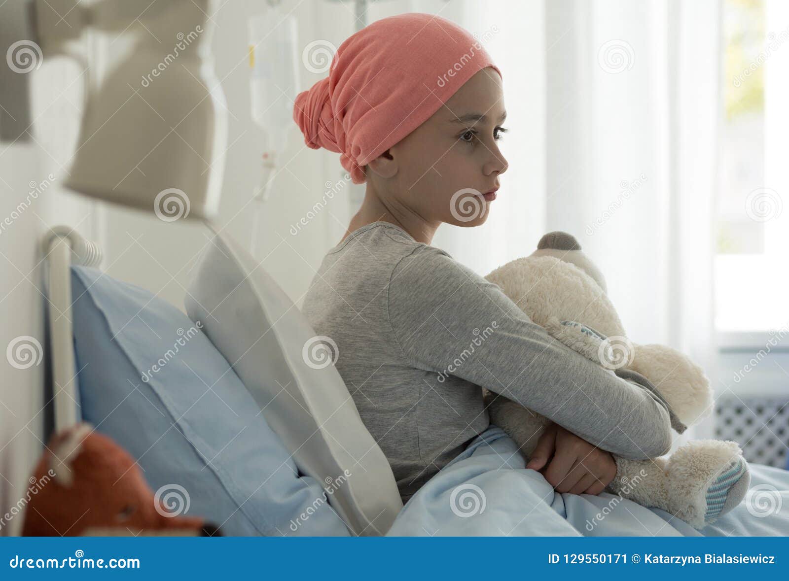 sick child with cancer sitting in hospital bed