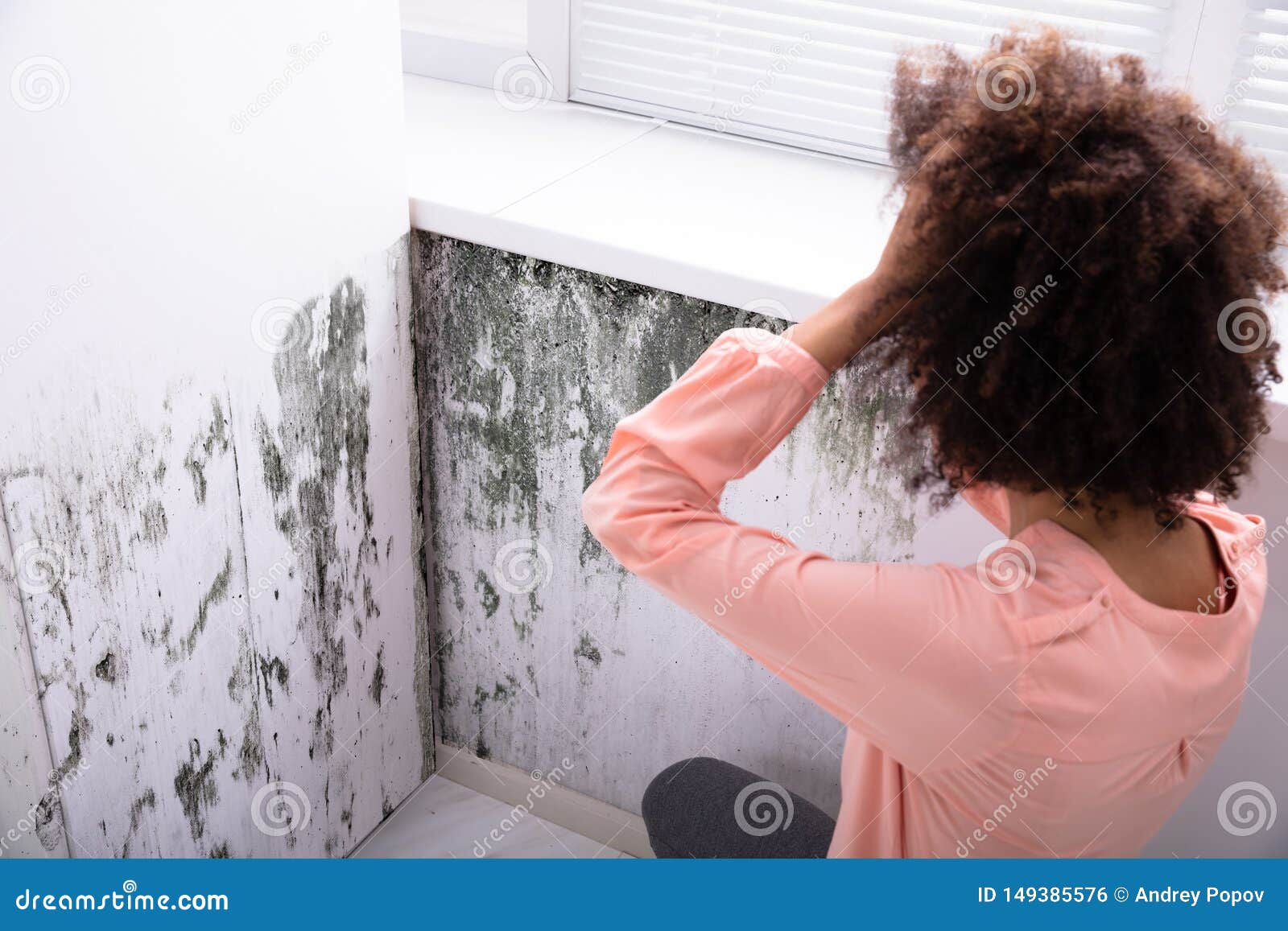 woman looking at mold on wall