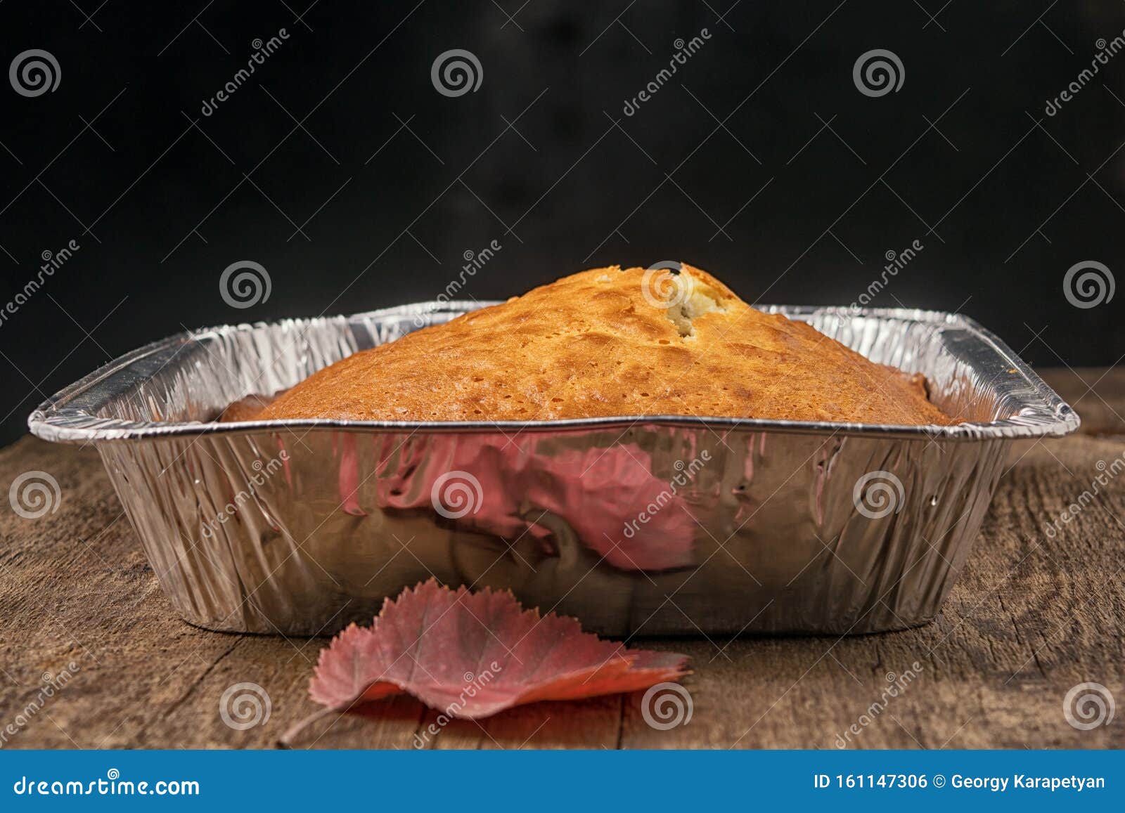 Side View of a Baked Pie in the Form of Thick Aluminum Foil on a Wooden