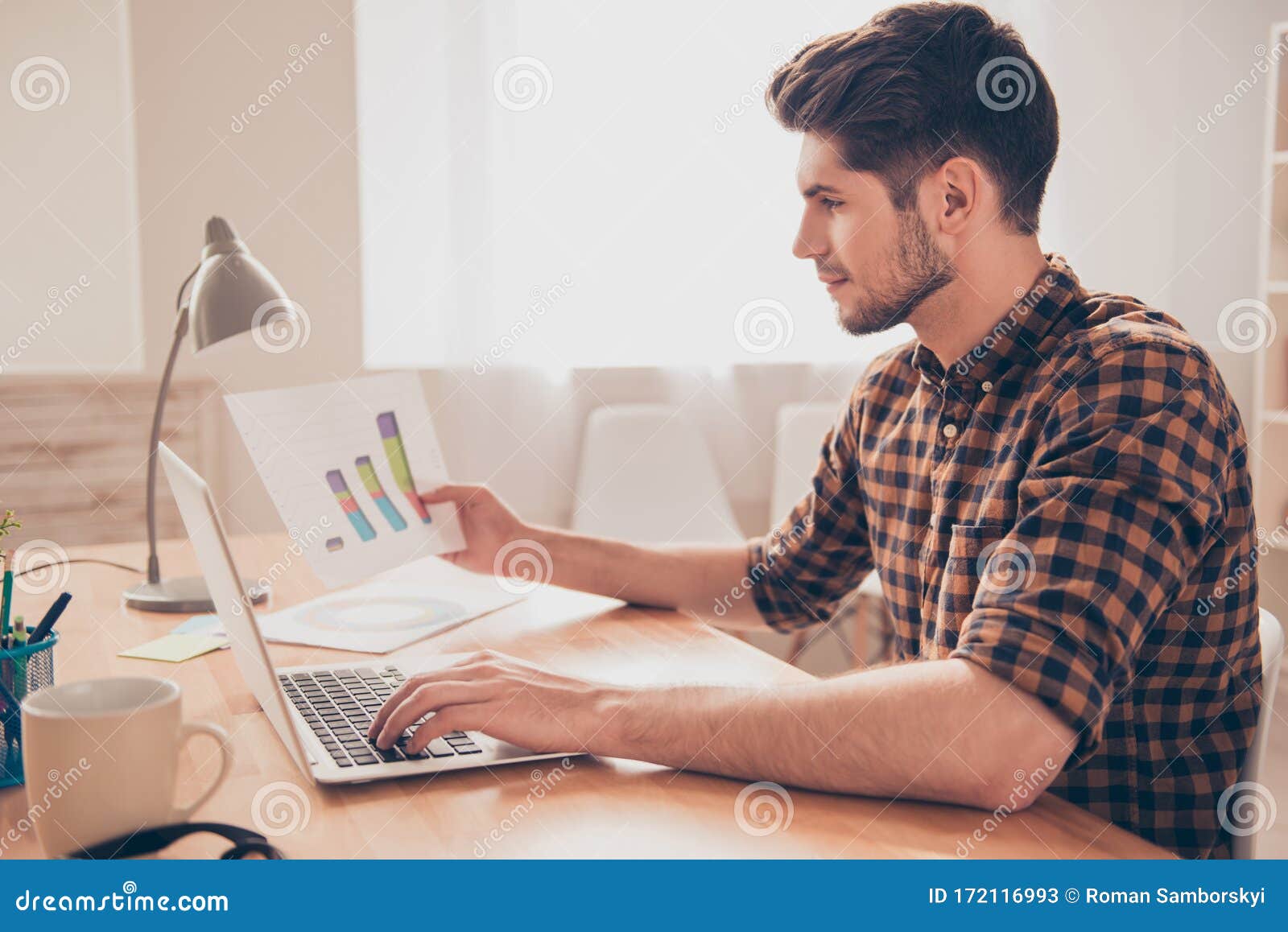 side view of concentrated young man working with laptop and diagrama