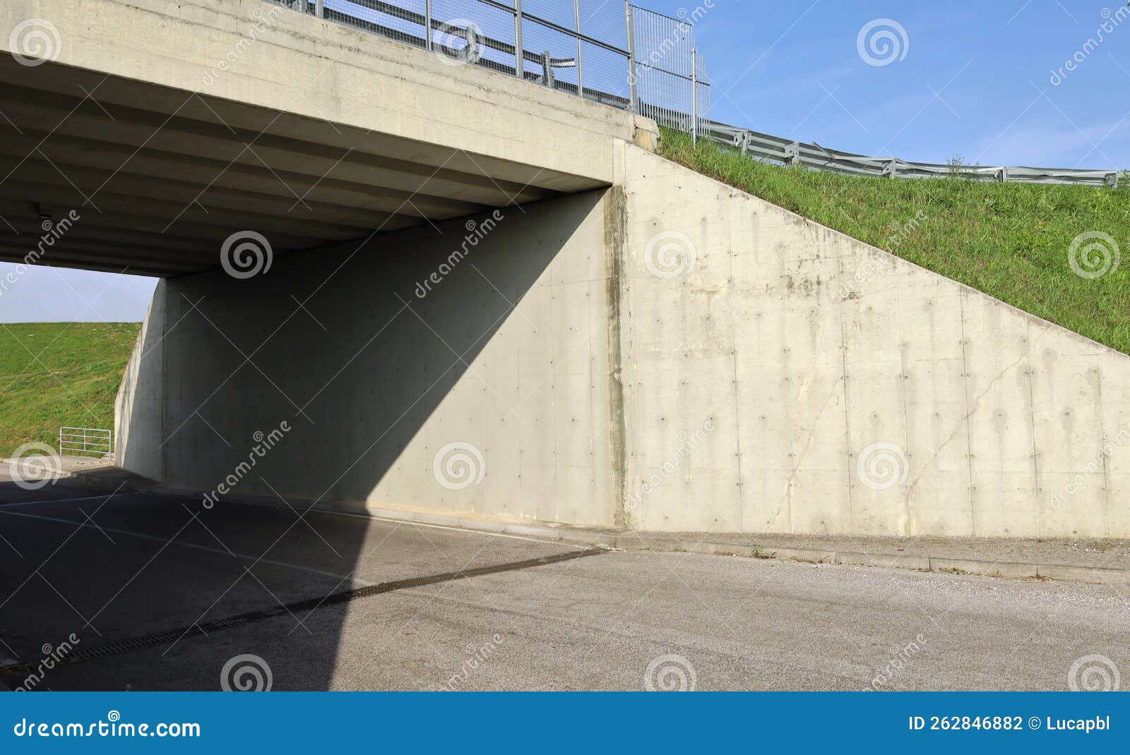 Side View of a Concrete Road Bridge, with Grass and Guard Rail in 