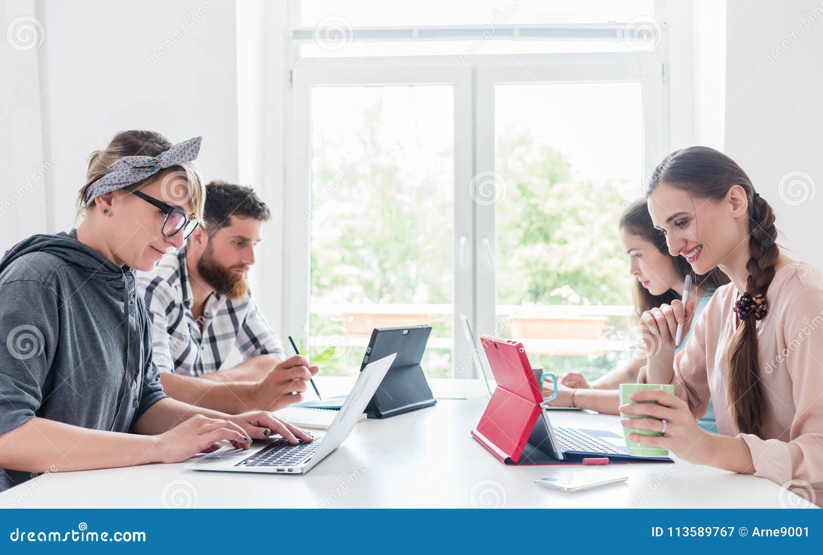 dedicated young people sharing a desk while telecommuting