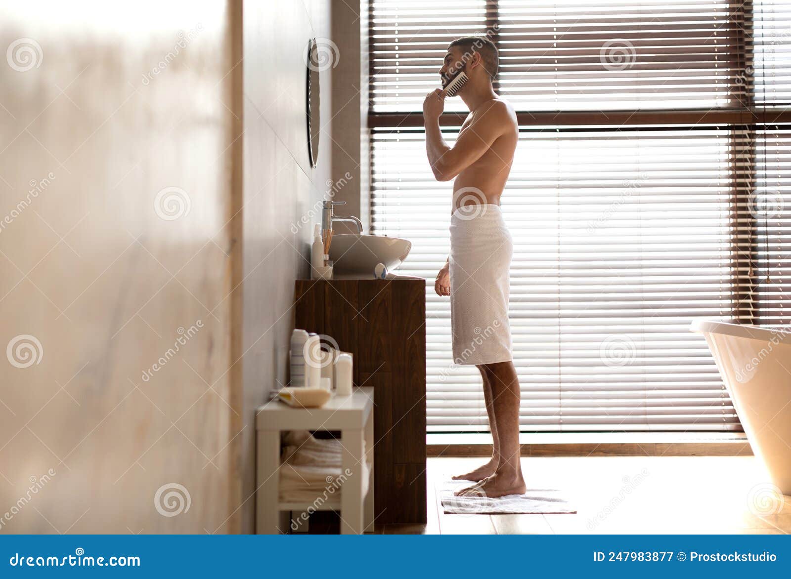 side view of guy looking in mirror brushing beard