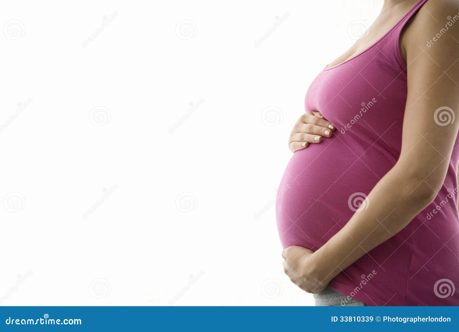 side view midsection of pregnant woman with hands holding tummy