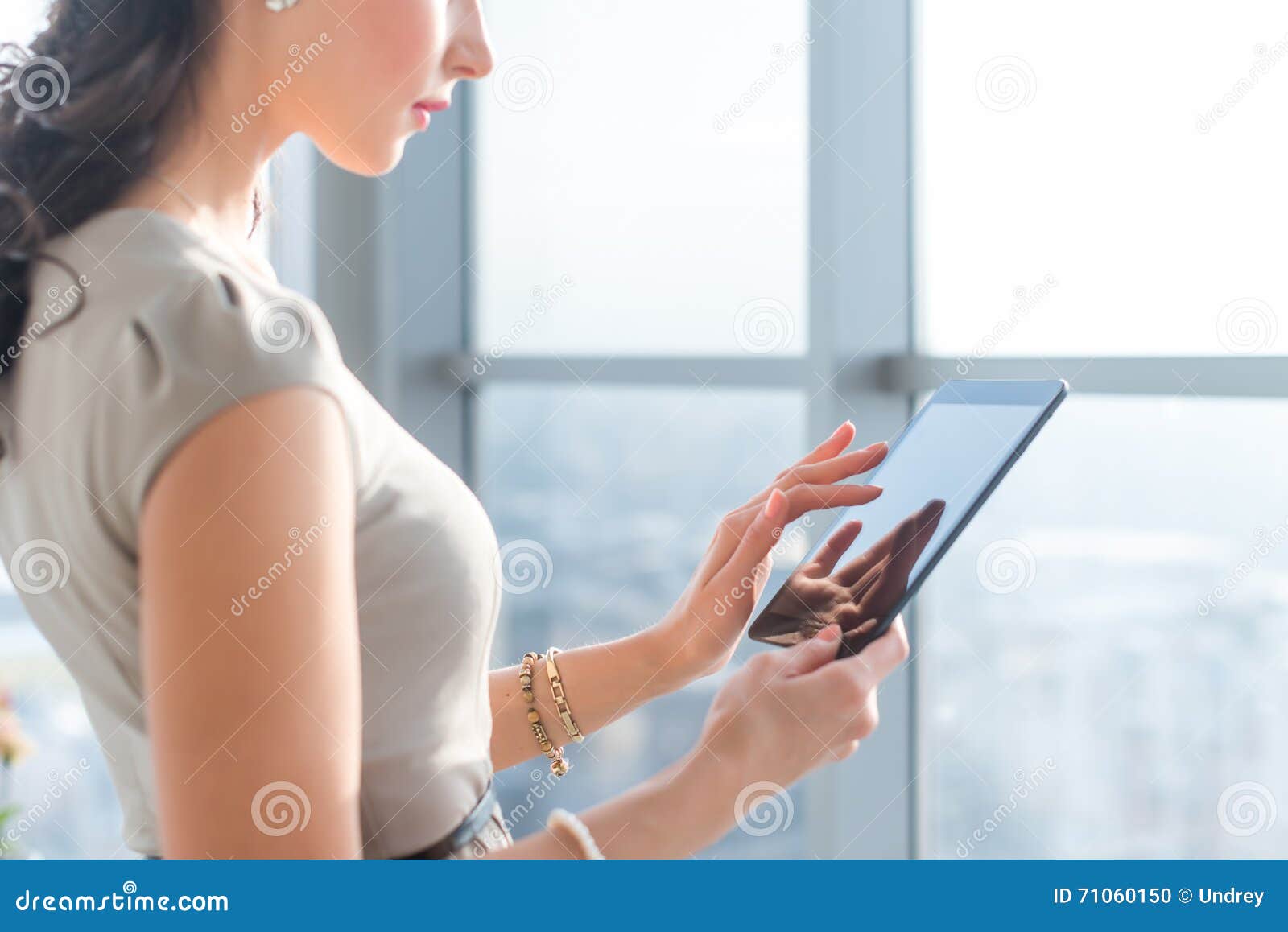 side view photo of young female teleworker using tablet, searching and browsing information via wi-fi connection