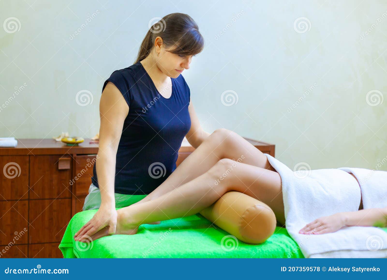 Side View Of Professional Massage Therapist Giving Massage On Woman Legs In The Spa Salon Stock