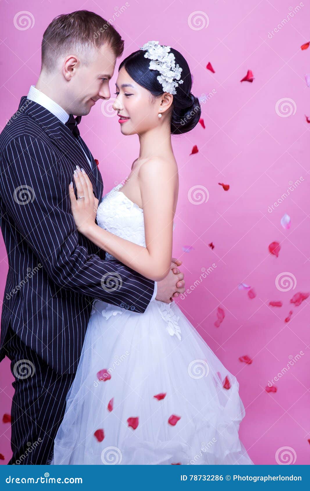 Side View Of Romantic Wedding Couple Embracing Against Pink Background