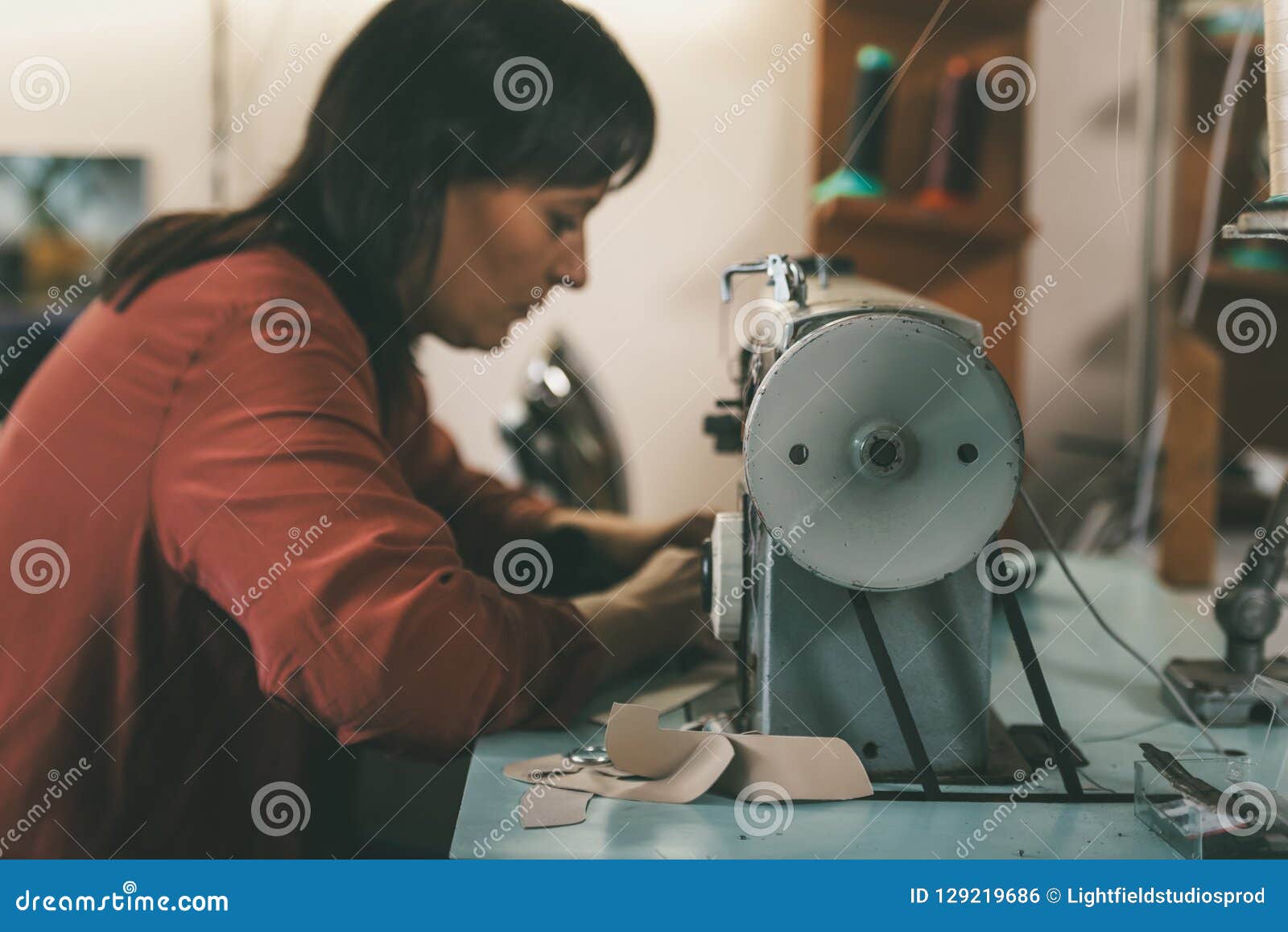 Side View of Seamstress Working with Sewing Machine and Leather at