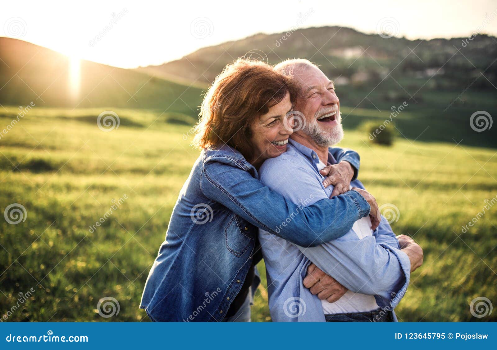side view of senior couple hugging outside in spring nature at sunset.