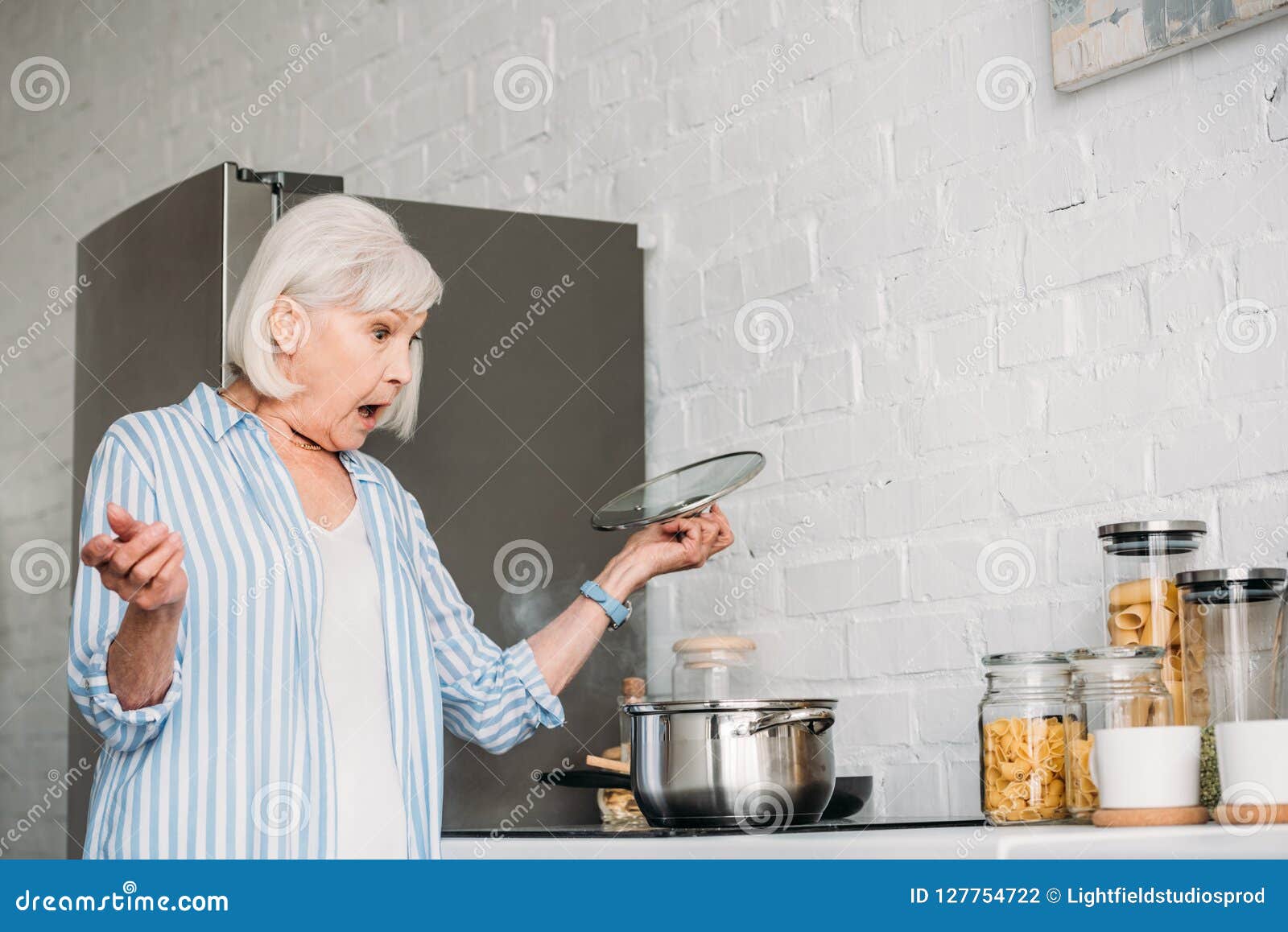 Side View of Shocked Senior Lady Checking Saucepan on Stove Stock Photo