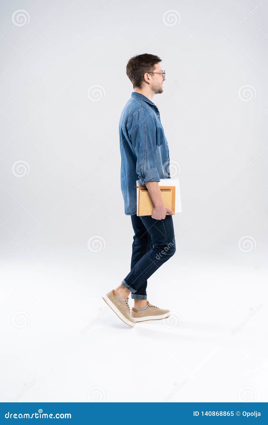 Side View of a Smiling Young Casual Man Walking, Student with Book Ang ...