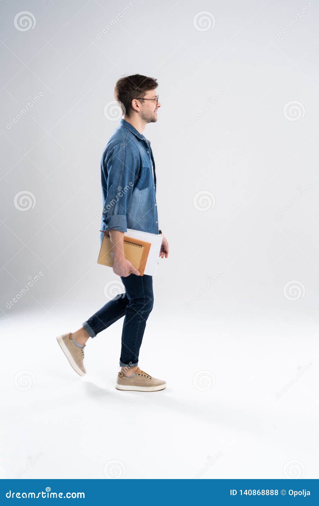 Side View of a Smiling Young Casual Man Walking, Student with Book Ang ...