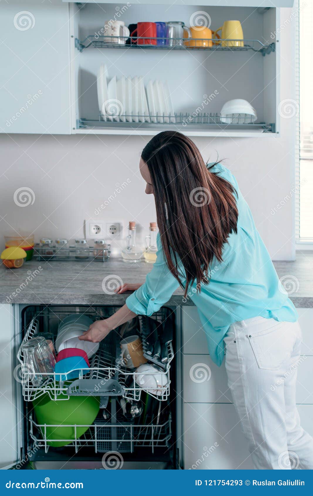 Side View of the Woman Pulls Clean Dishes from the Dishwasher Stock
