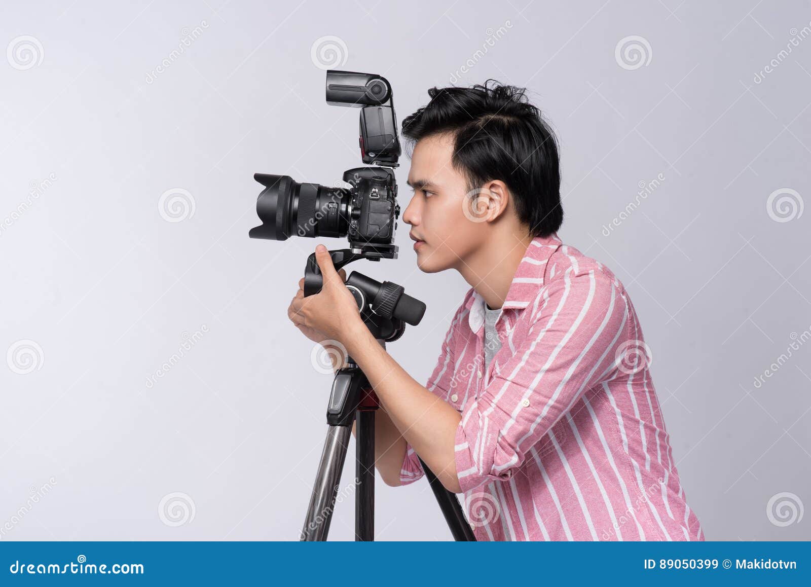 Side View of Young Asian Photographer Holding Digital Camera, while