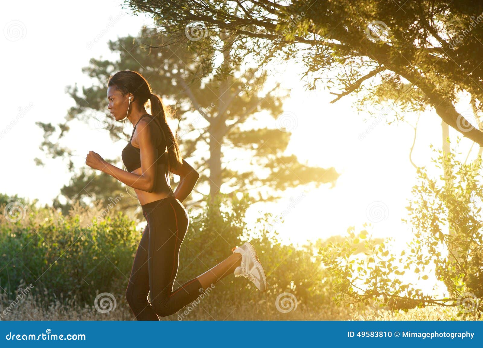 Fit Beautiful Young Woman Running In The Park. She Is Wearing