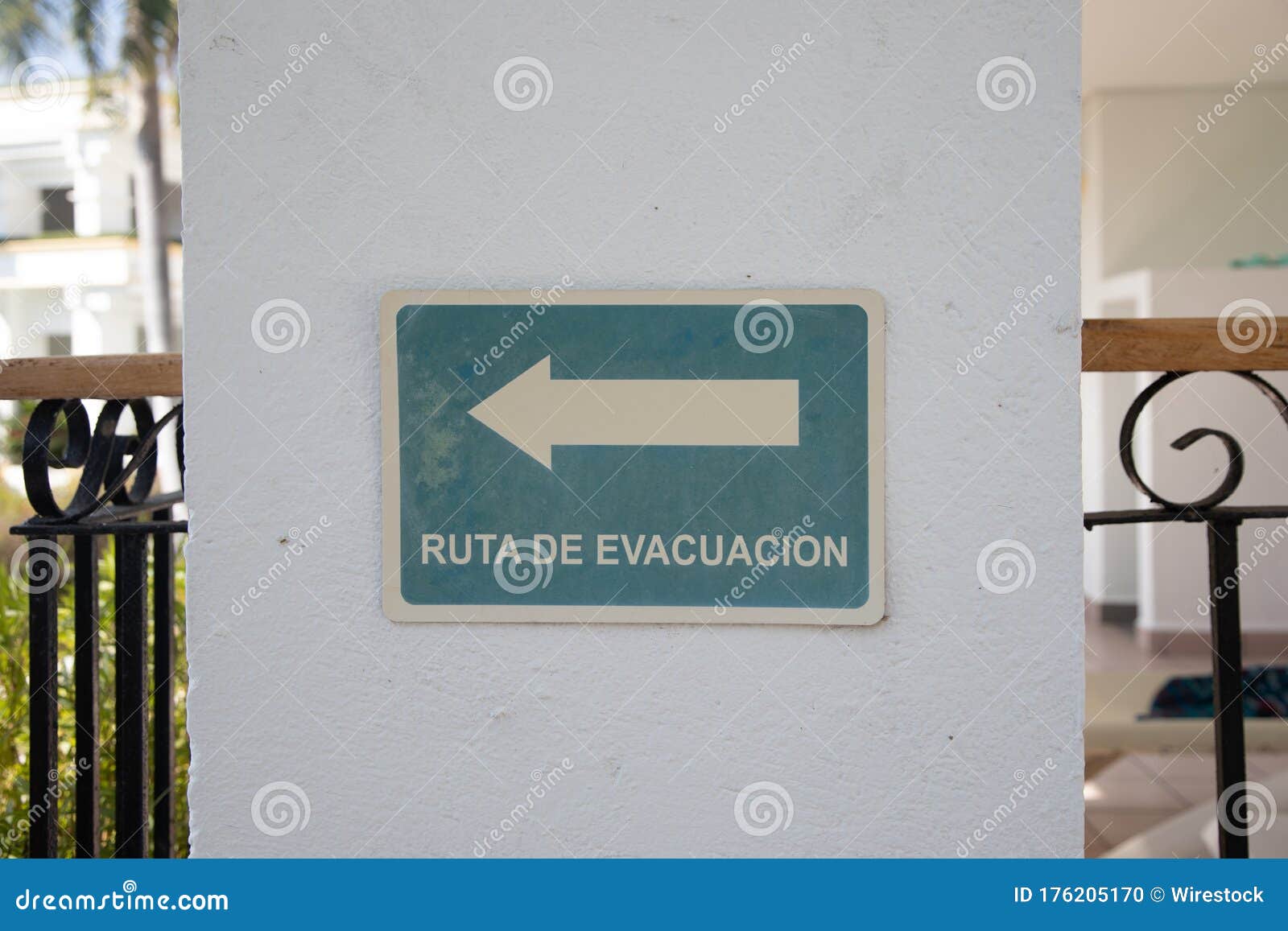 sign with an arrow and a ruta de evacuacion - evacuation route - text on a white wall