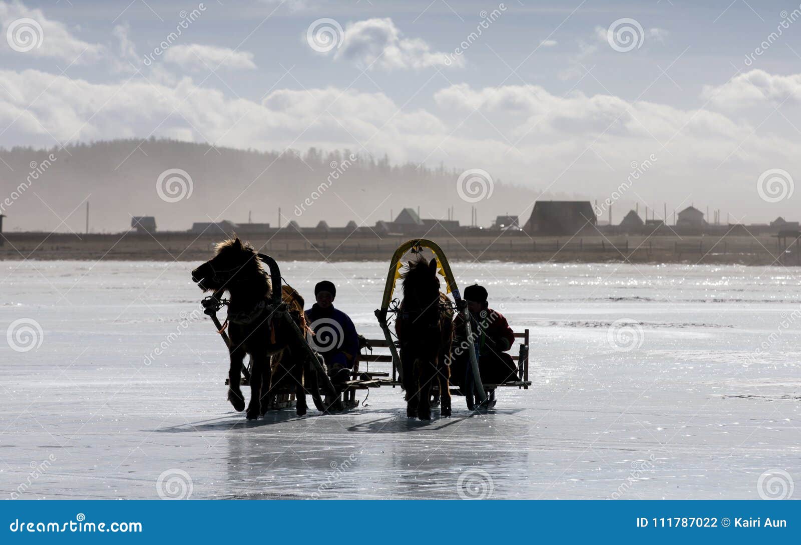 sihouette of men riding on a horse sledge on a frozen lake