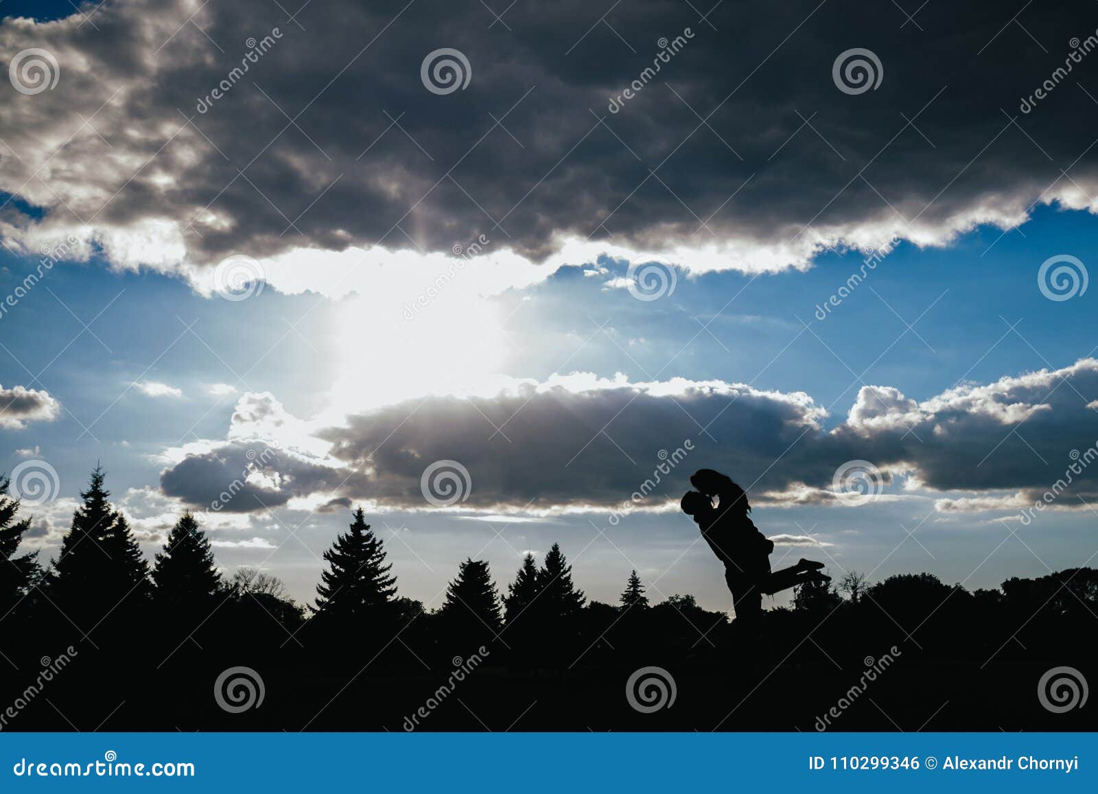 Silhouet van het koesteren van kerel en meisje. Een kerel die een meisje in zijn wapens, een silhouetkader bij zonsondergang houden