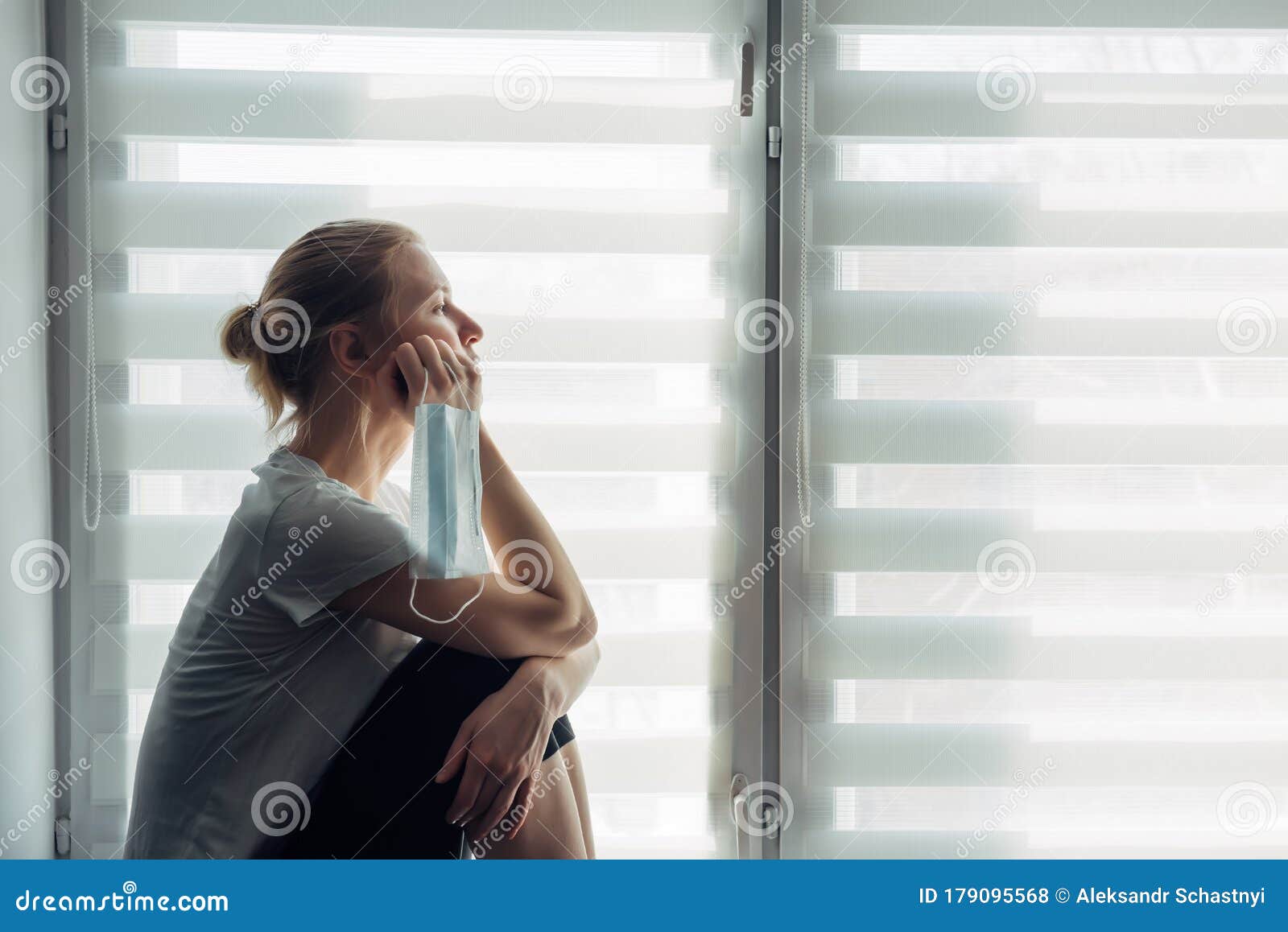 silhouette of alone woman sitting on the windowsill on the background of window. quarantine, self-isolation, stay at home. concept