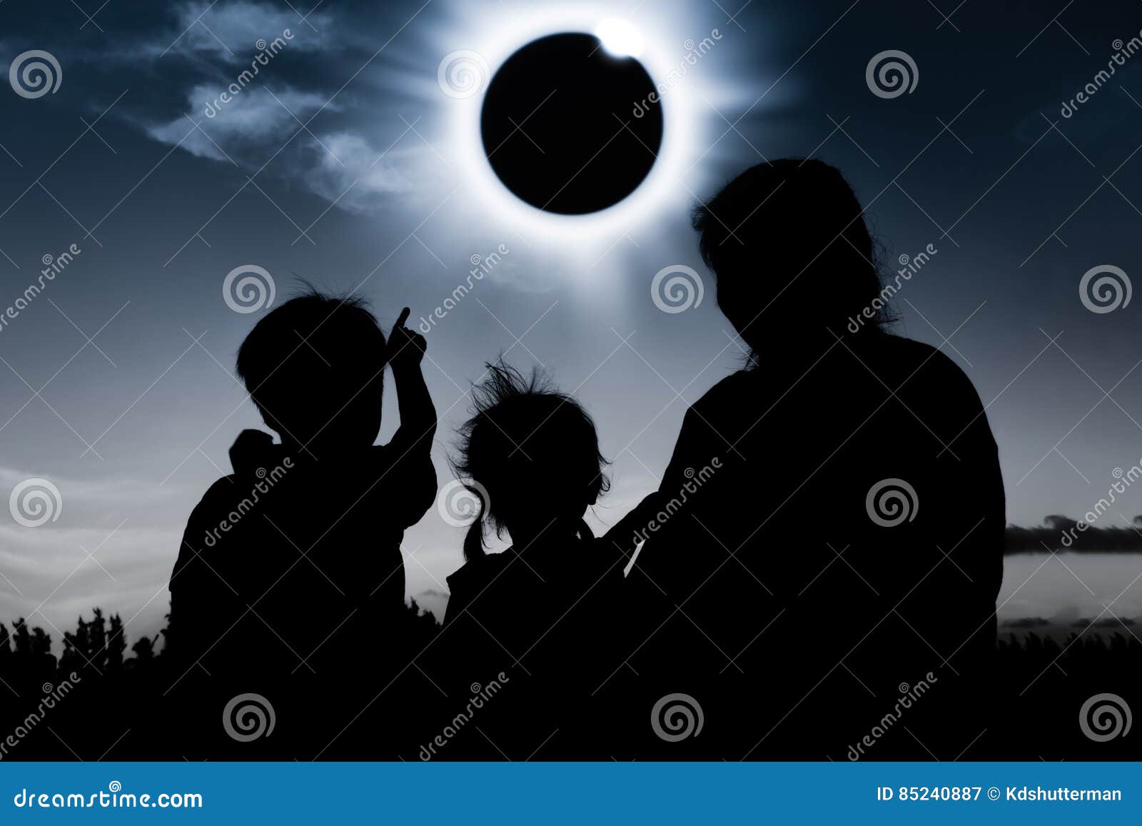 silhouette back view of family looking at solar eclipse on dark