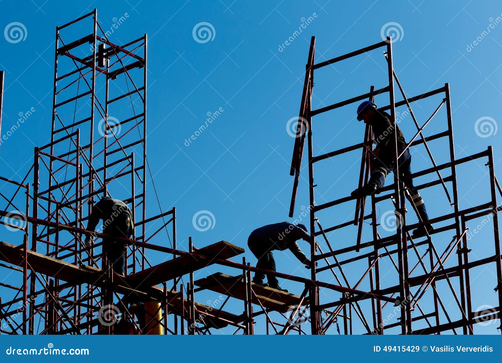 silhouette of construction workers against sky on scaffolding wi