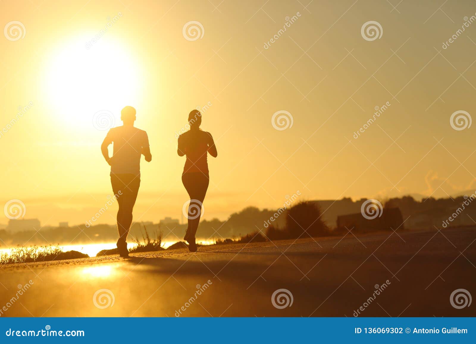 couple practicing sport running at sunset on the road