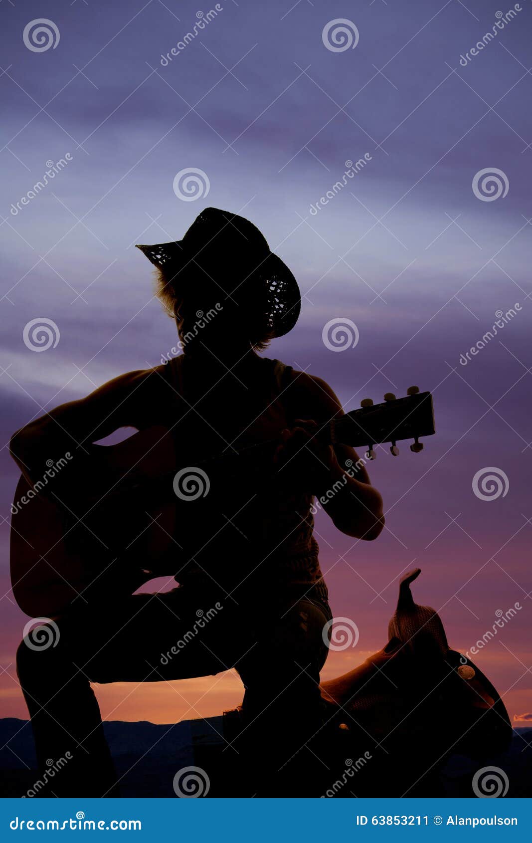 Silhouette of a cowboy sitting on a saddle playing a guitar. A silhouette of a cowboy kneeling by his saddle playing his guitar.