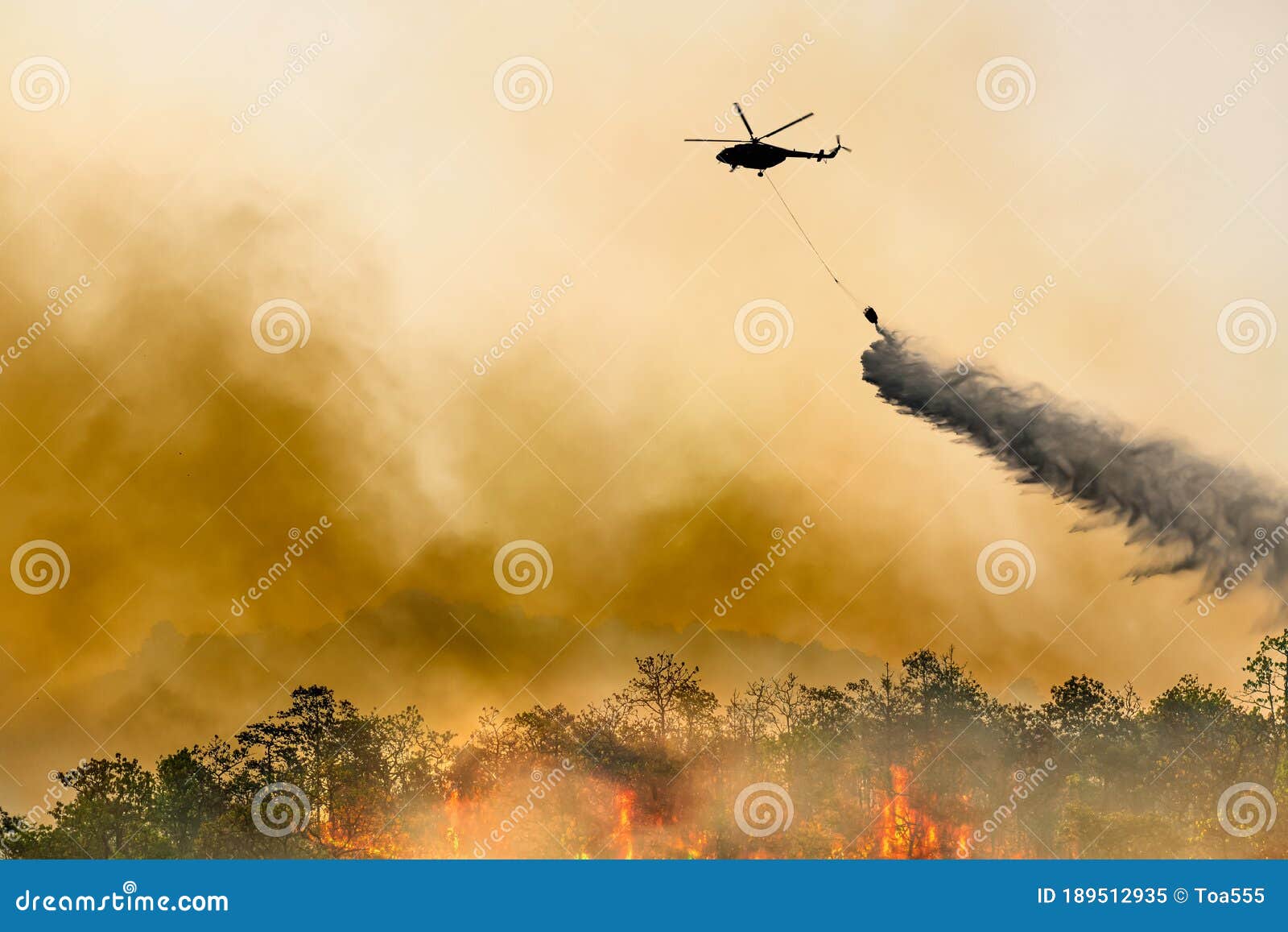 silhouette firefithing helicopter dumps water on forest fire
