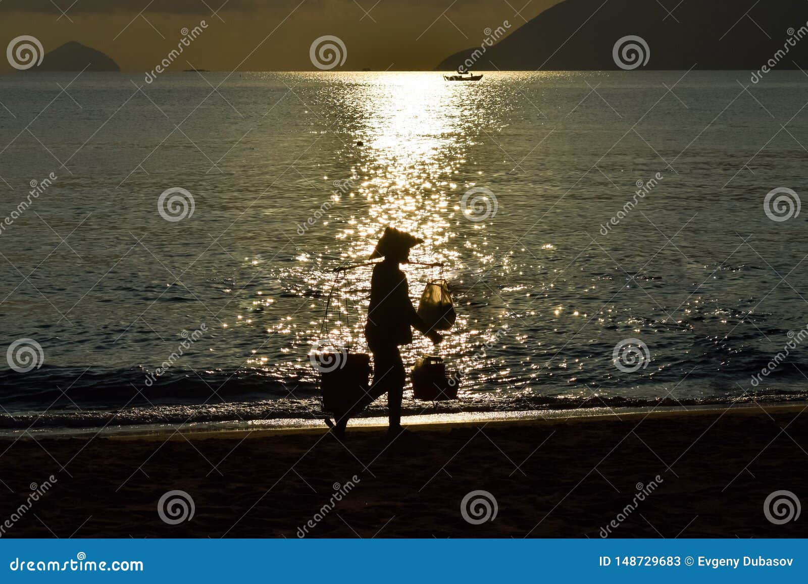silhouette of food vender against reflection of sun beam on the beach at dawn