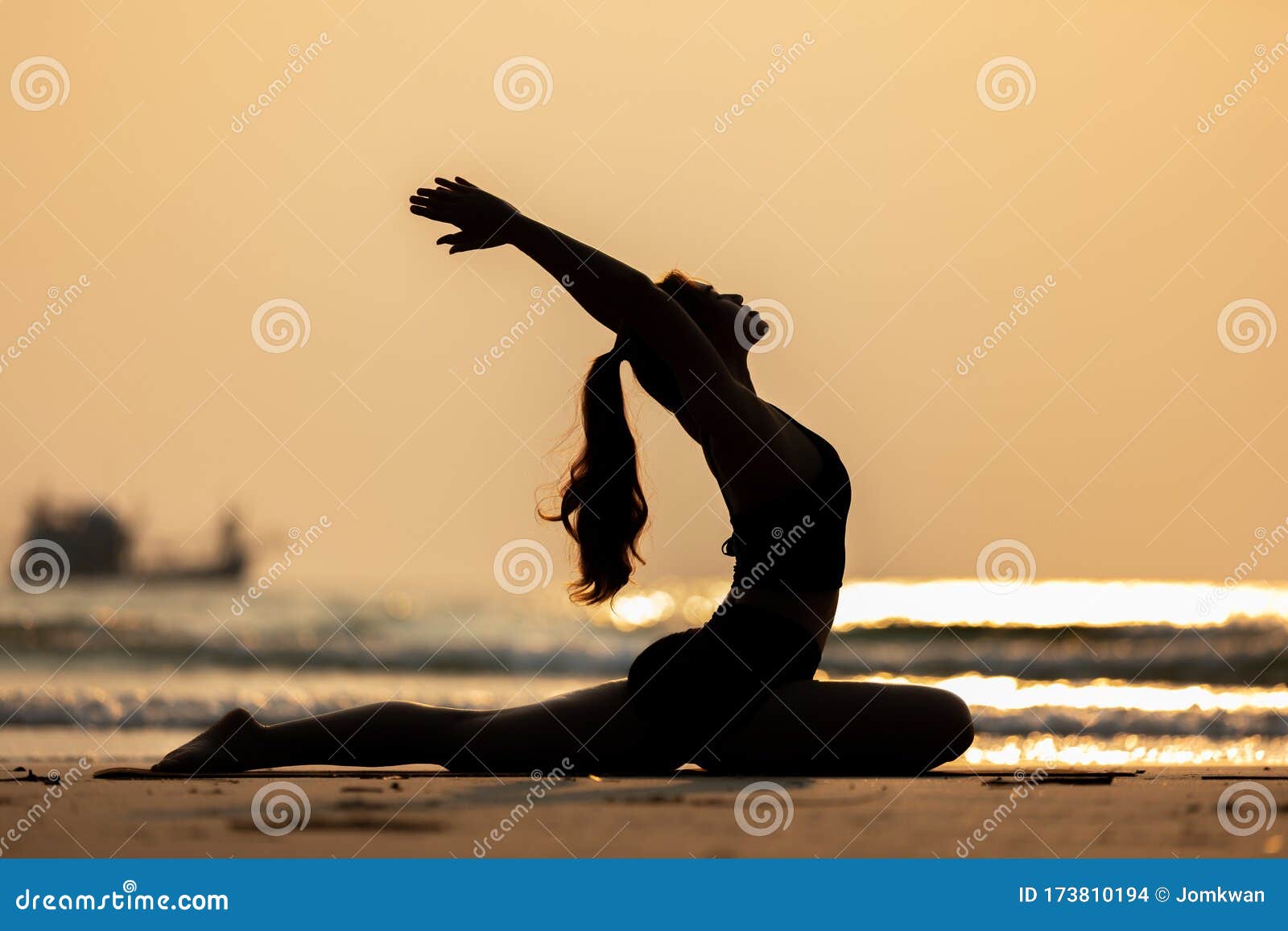 Sporty woman doing king pigeon yoga pose on the beach stock photo