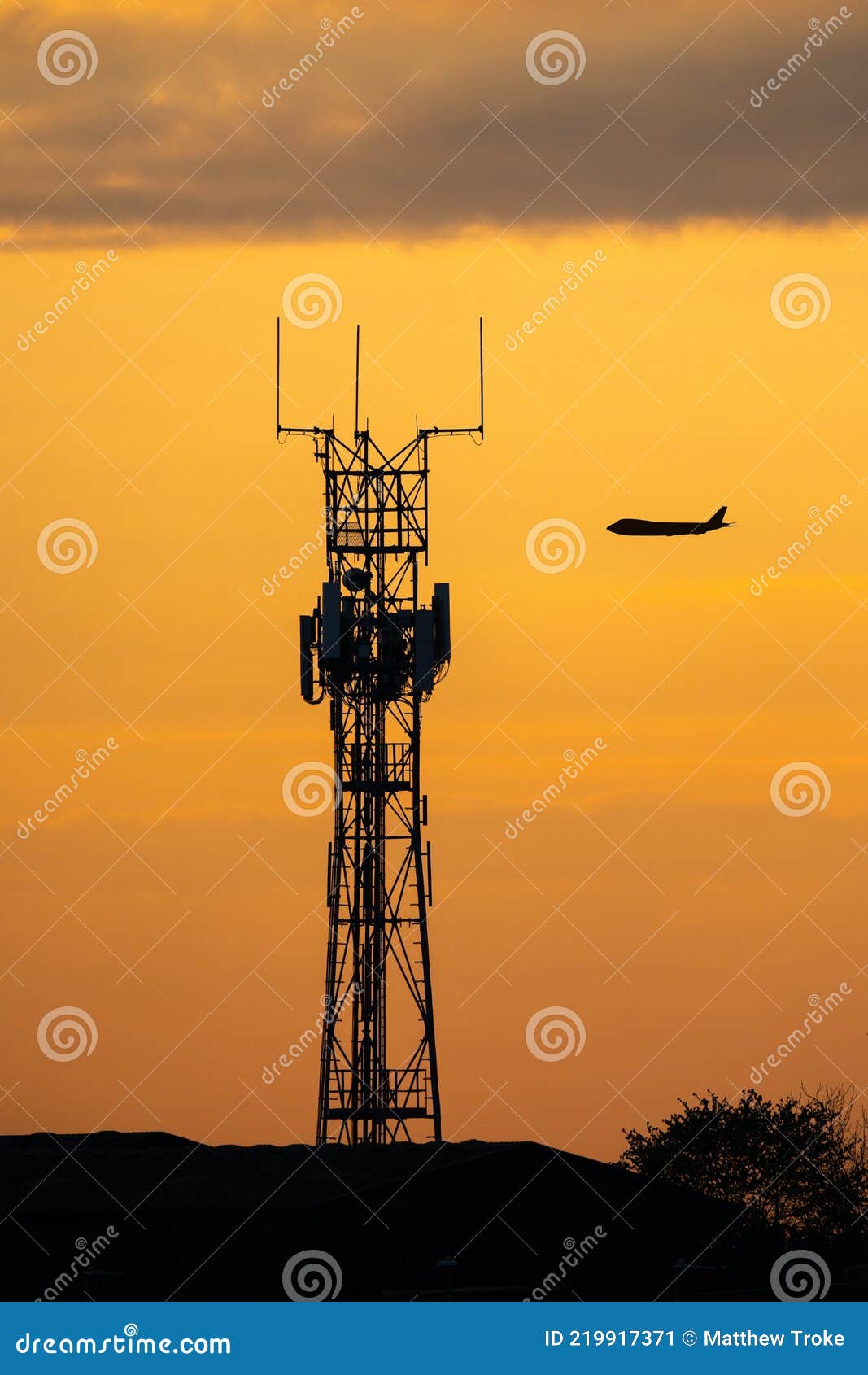 silhouette jumbo jet flying sunset behind high tech radio mast for communications between pilot and airport. air traffic control