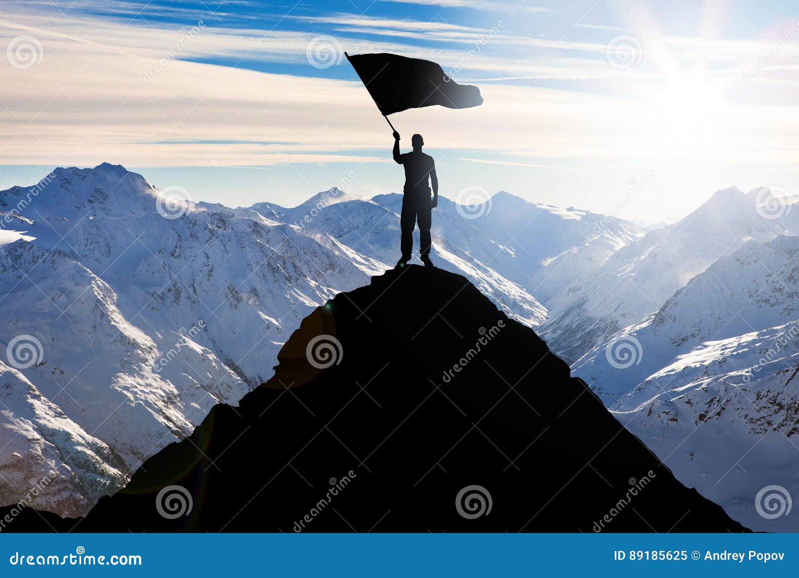 Silhouette of a Man with Flag Standing on Mountain Peak Stock Image