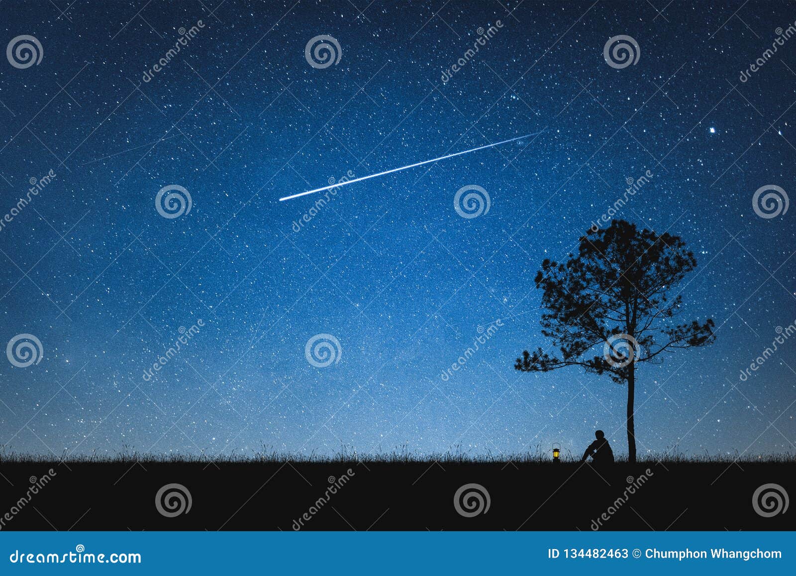 silhouette of man sitting on mountain and night sky with shooting star. alone concept