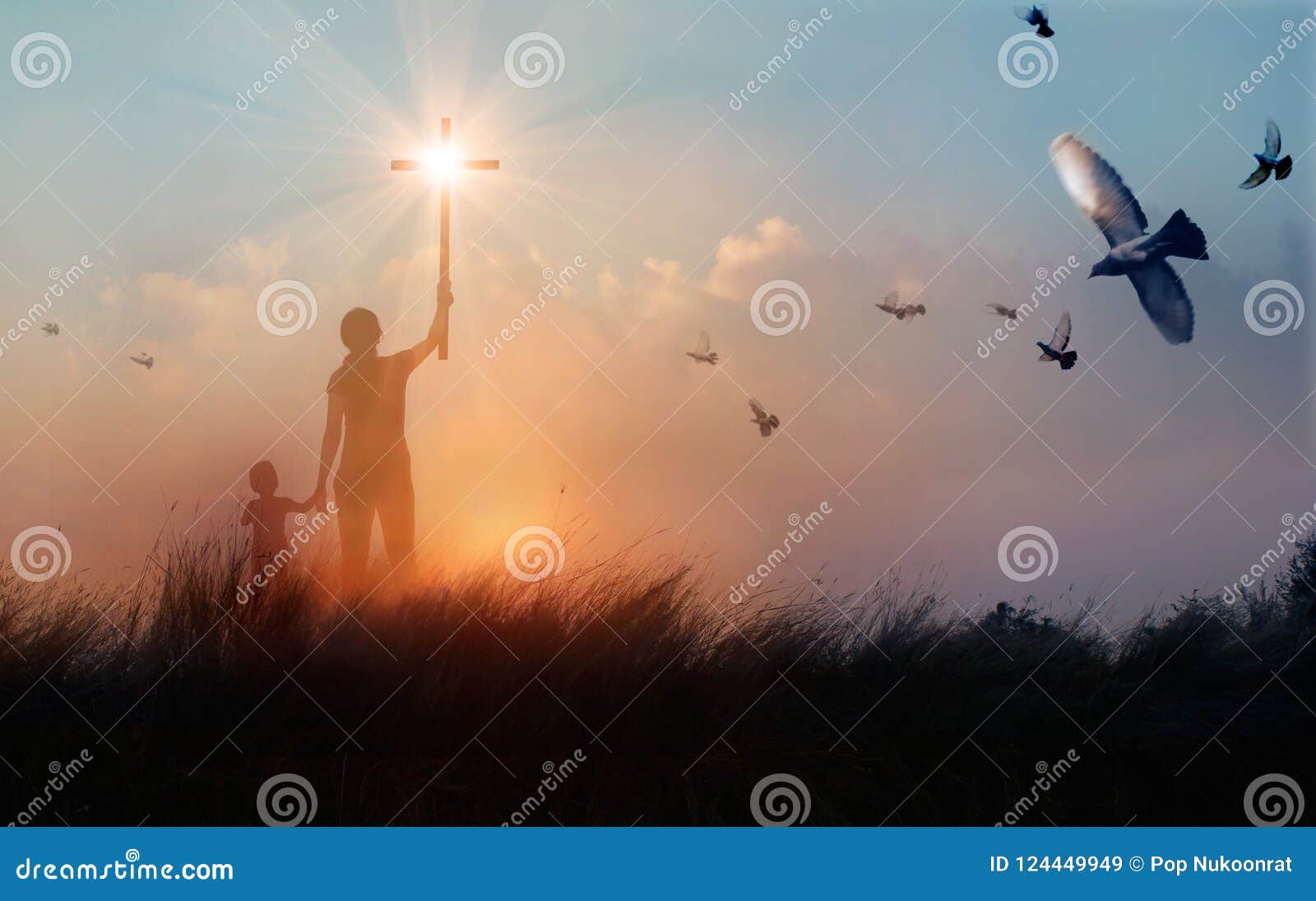 silhouette of mother and son christian prayers raising cross while praying to the jesus on sunset background, worship concept