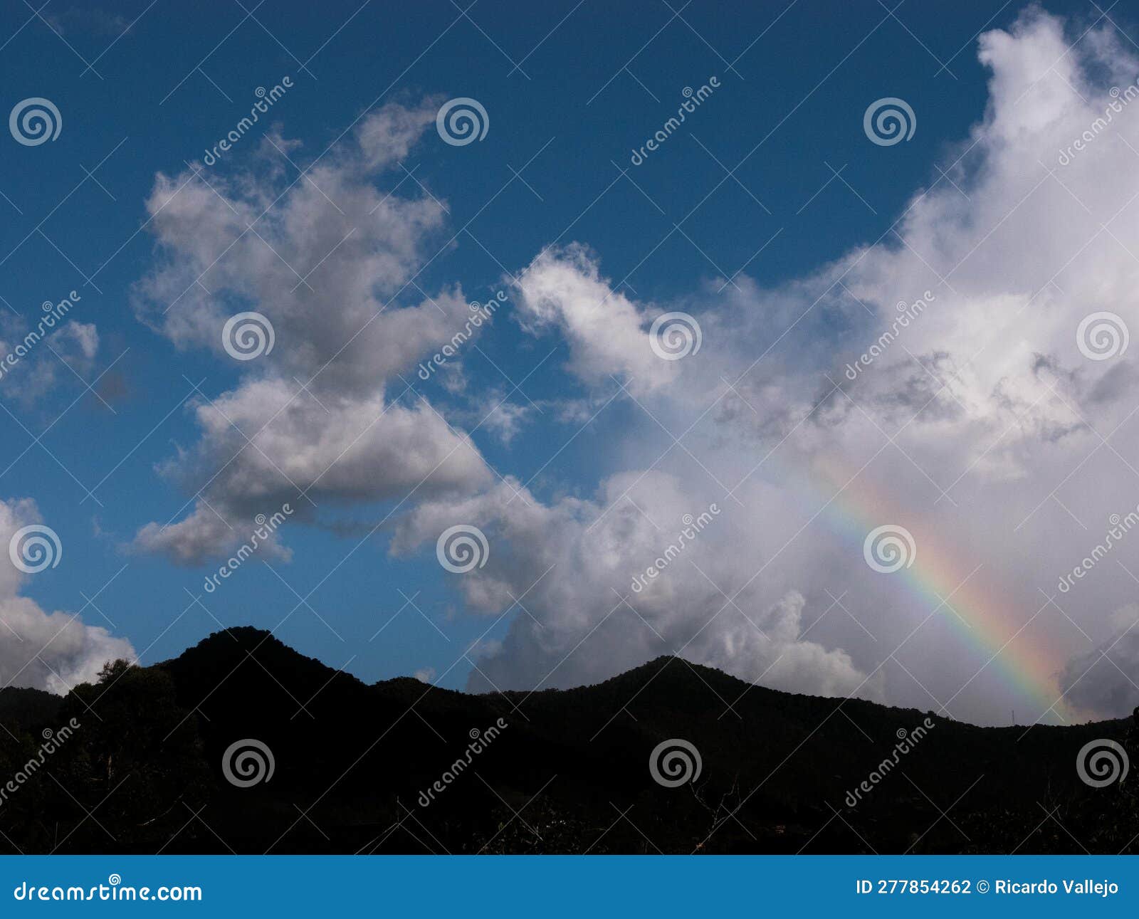 silhouette of mountain with rainbow and clouds
