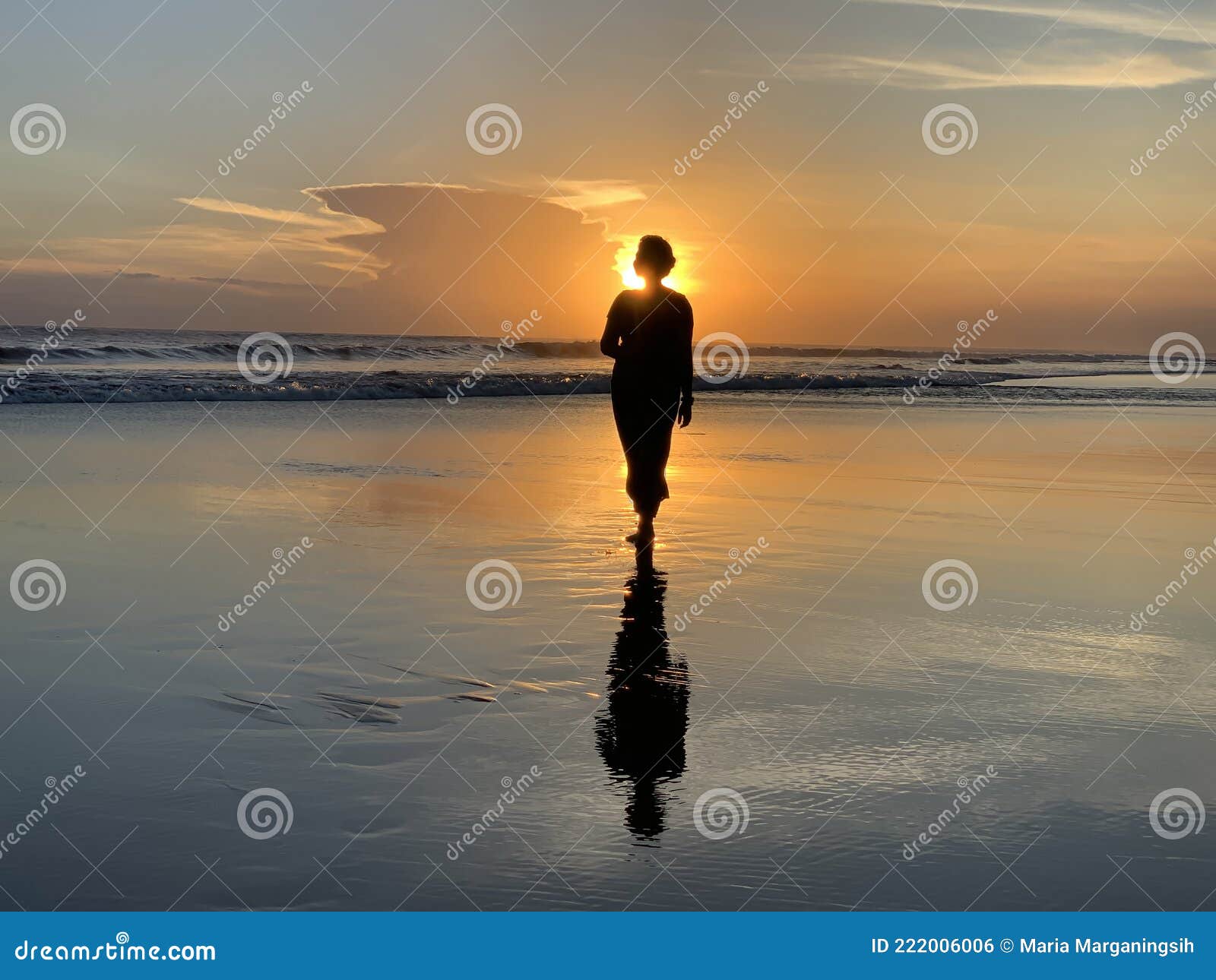 silhouette of the person walking alone in the beach at sunset. fragility and loneliness concept.