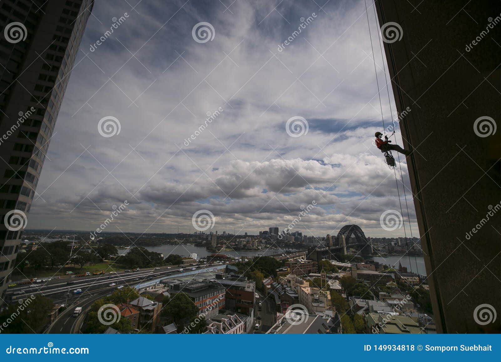 silhouette picture of construction rope access worker wearing a hard hat, full body safety harness working at height, abseiling