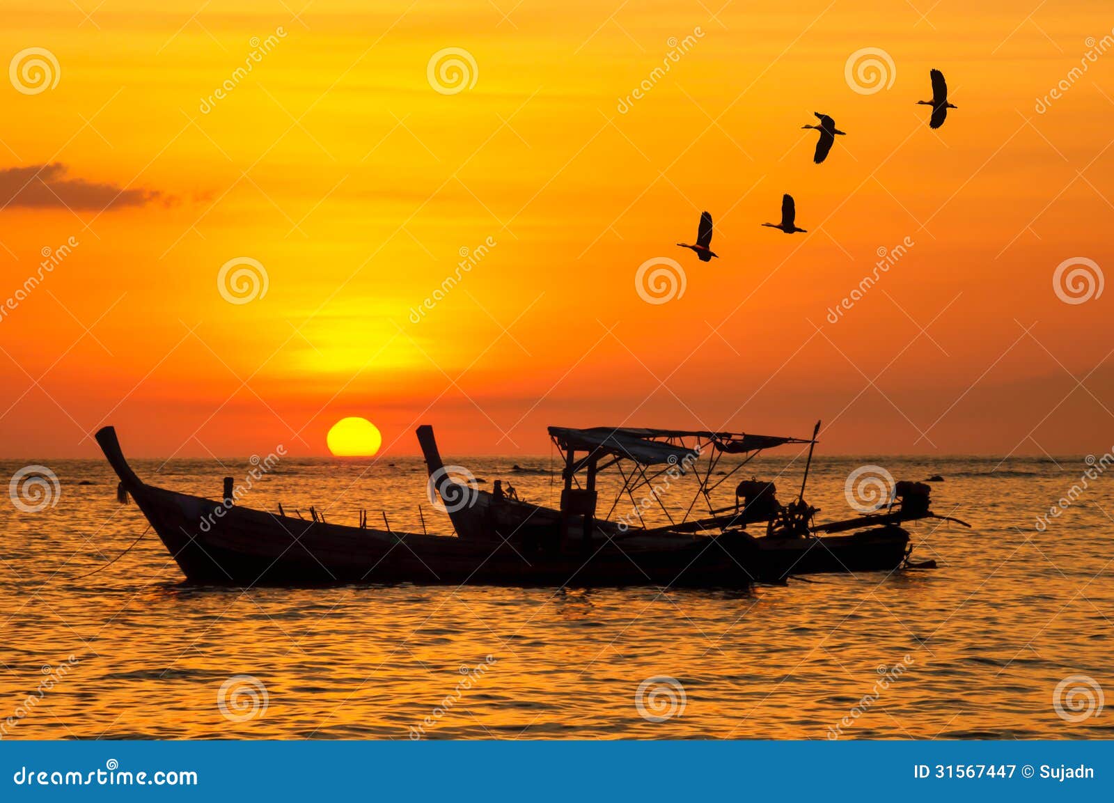 silhouette small fishing boat with birds and sunsets stock