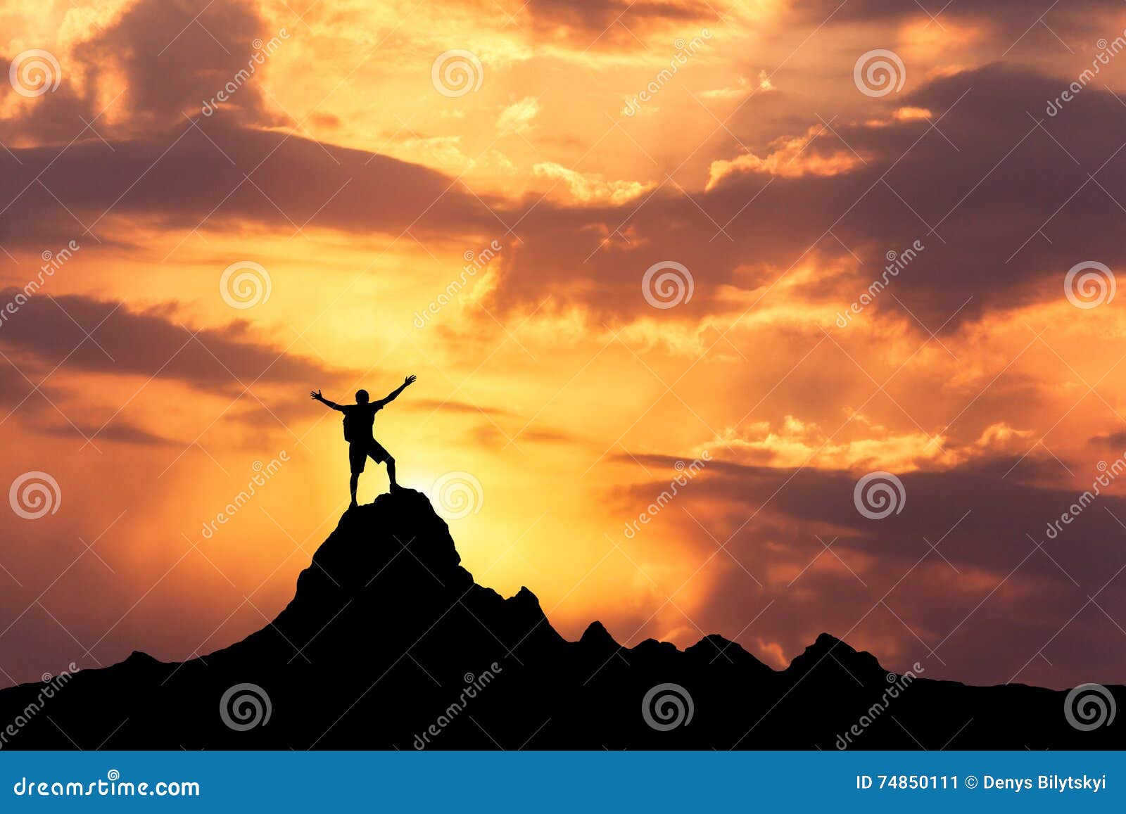 silhouette of a standing happy man on the mountain peak