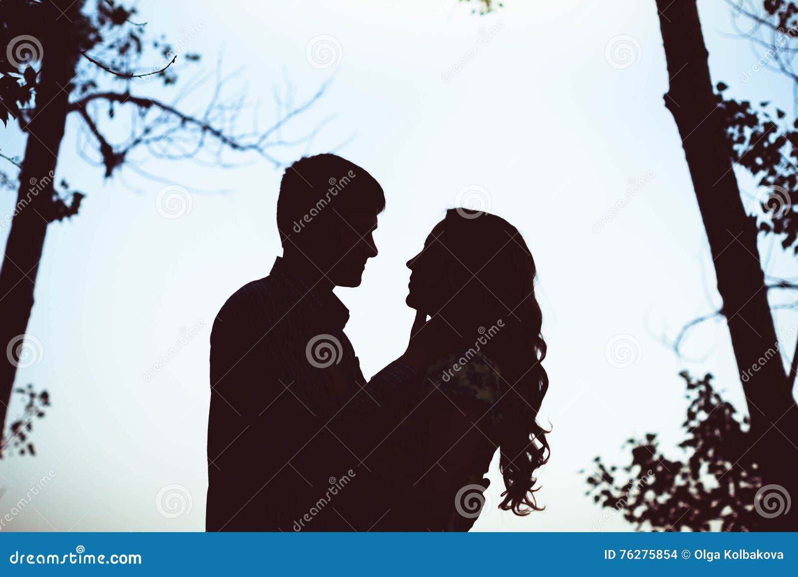 silhouette of two lovers embracing in the forest.