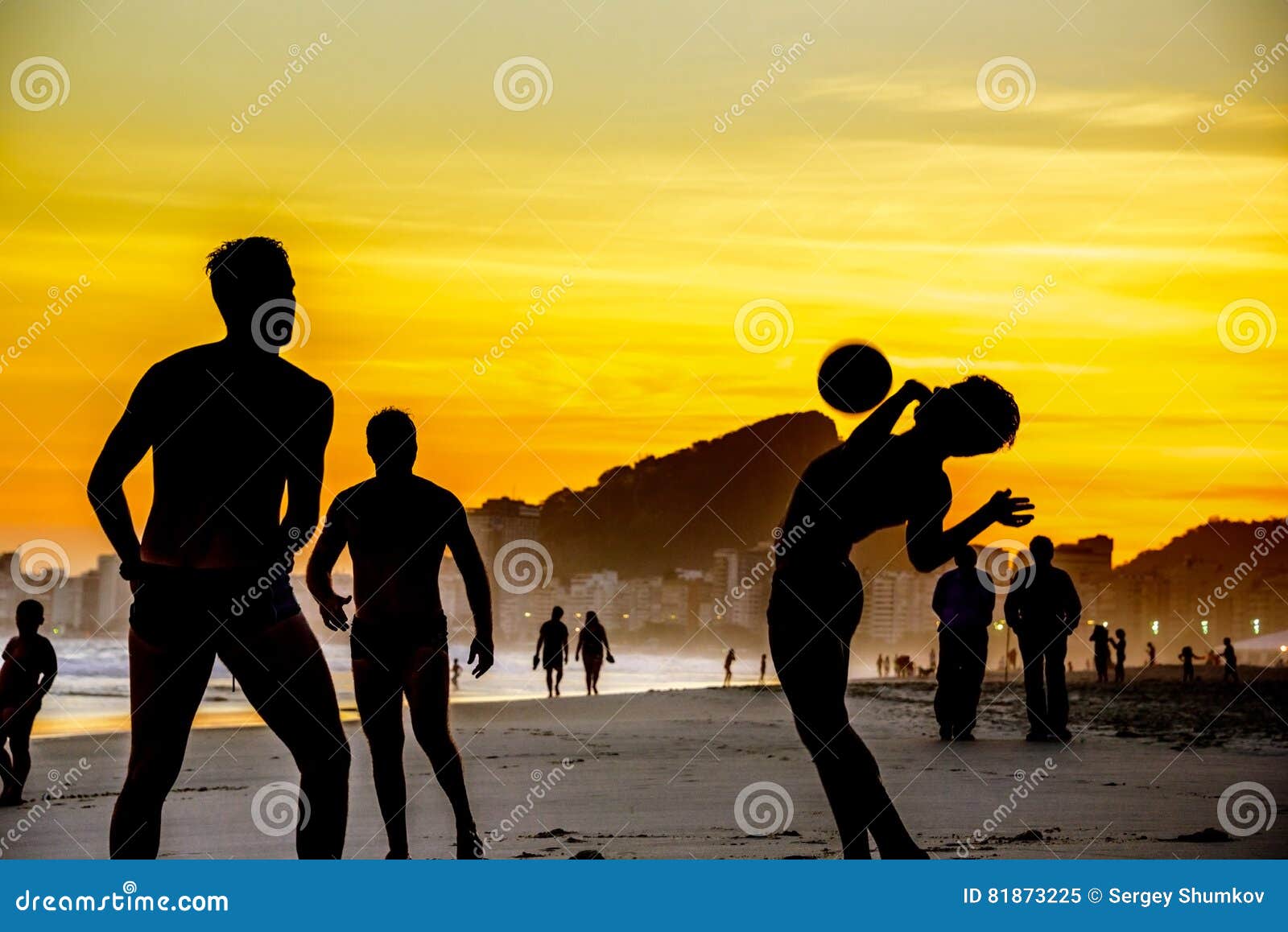 Silhouetten van mensen die strandvoetbal op de achtergrond van mooie gouden zonsondergang spelen bij Copacabana-strand, Rio de Ja. Silhouetten van mensen die strandvoetbal op de achtergrond van mooie gouden zonsondergang, de Atlantische Oceaan en silhouetten van lopende mensen spelen bij Copacabana-strand, Rio de Janeiro, Brazilië