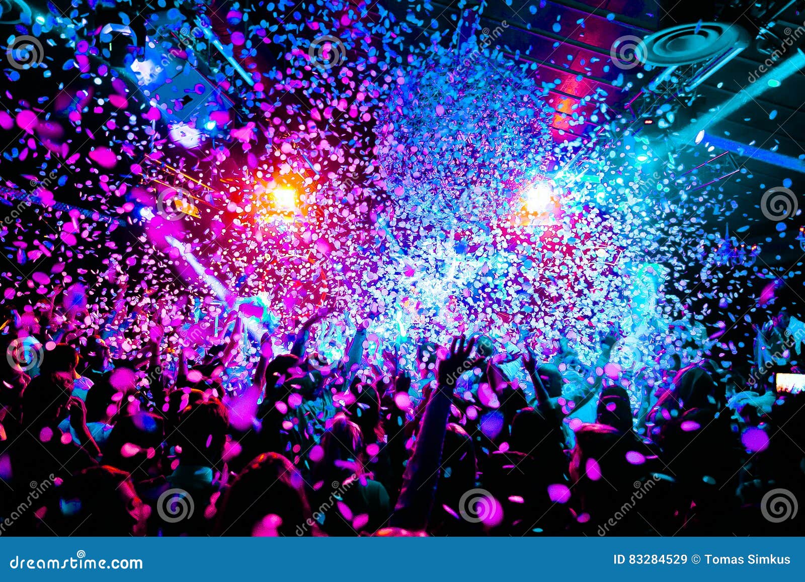 silhouettes of concert crowd in front of bright stage lights with confetti