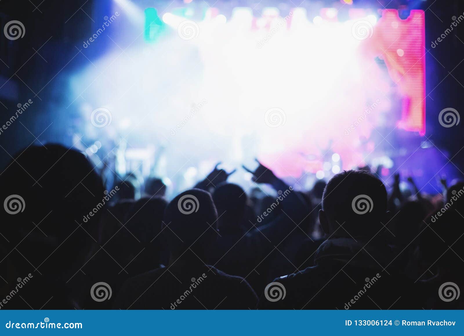 Silhouettes of a Concert Crowd in Front of an Illuminated Stage in a ...